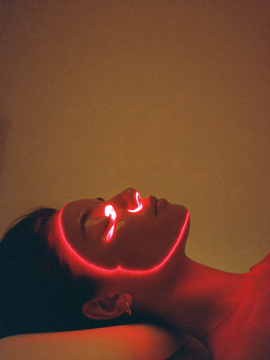 Warm red therapy light glowing softly across a woman's face as she rests